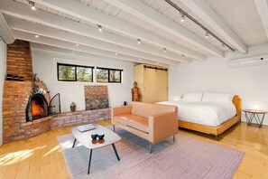 A modern bedroom with a bed, a sofa, a fireplace, and a window. - Eagle Dancer Upper Casita | Majestic Desert Views (Sedona)