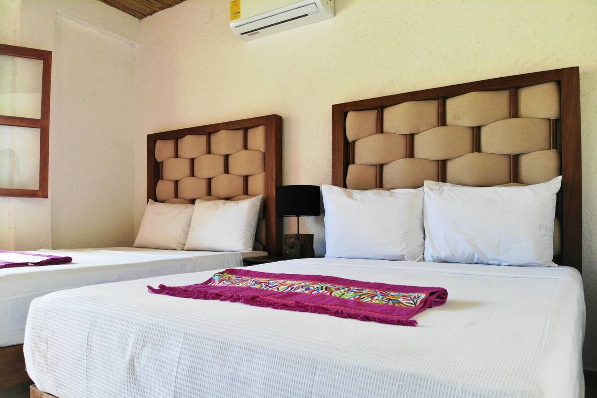 Una habitación de hotel con dos camas, cada una con cabecero de madera y ropa de cama blanca.