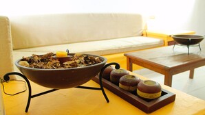 Un salón con sofá, una mesa de centro, un cuenco decorativo con plantas secas y una bandeja con velas.