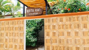 Un letrero de madera con la inscripción "KINTA KAO HOTEL BOUTIQUE" colocado en una pared sobre una entrada con azulejos.