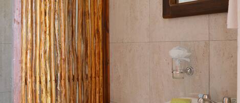 A bathroom with a wooden shower curtain, a toilet, a sink, and a mirror.