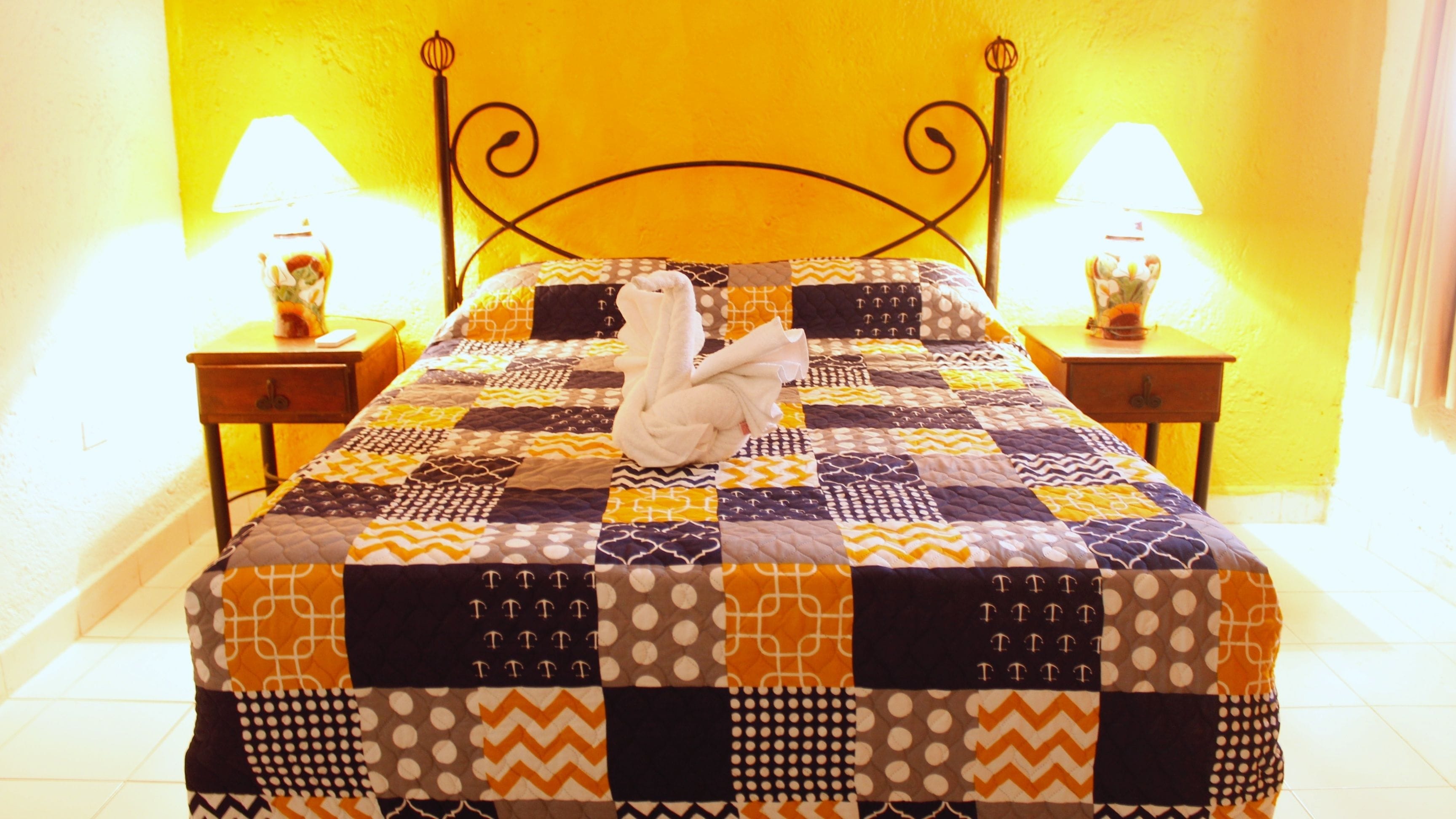 A bed with a quilt, two nightstands, and two lamps.