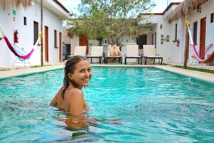Un área de piscina con sillas de descanso y hamacas.