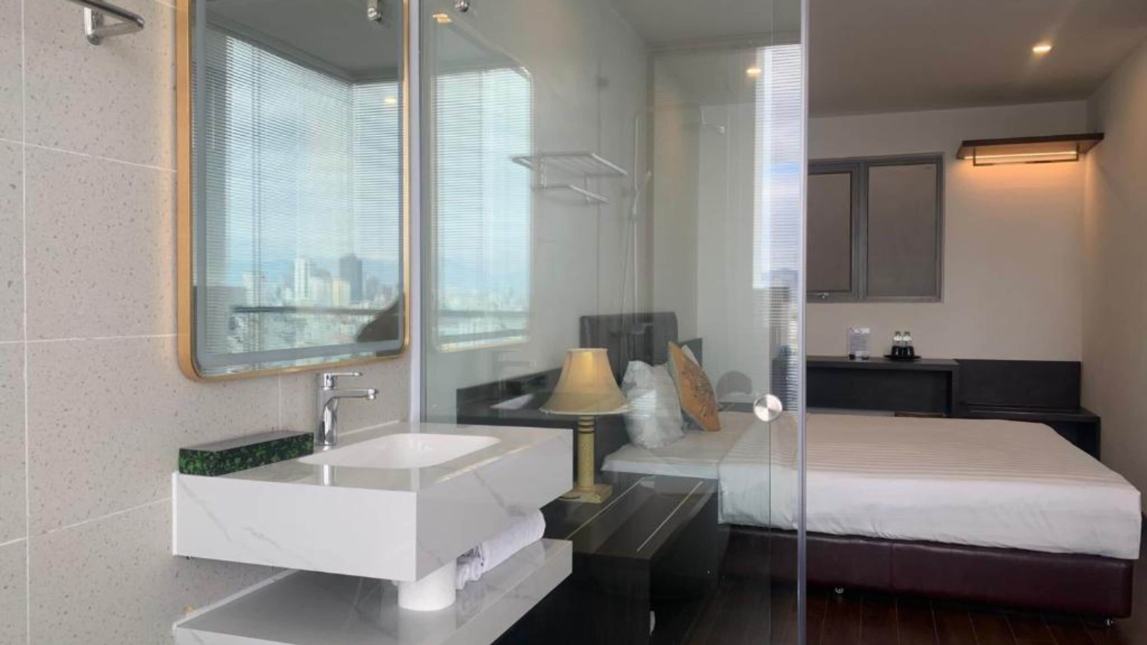 Une salle de bain moderne avec un grand miroir, un lavabo blanc et une douche à parois de verre.