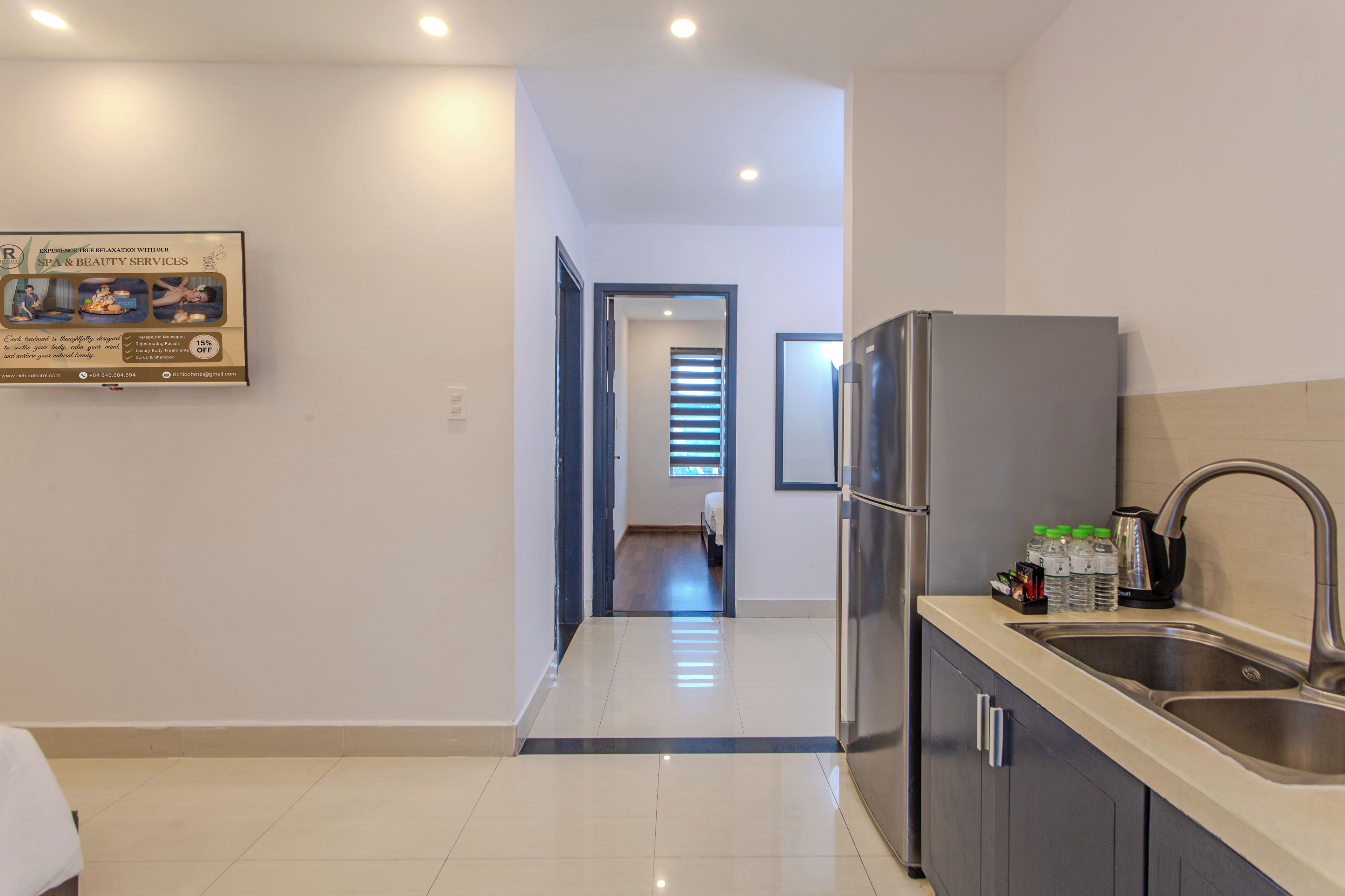 A modern kitchen with a stainless steel refrigerator, a sink, and a countertop with water bottles.