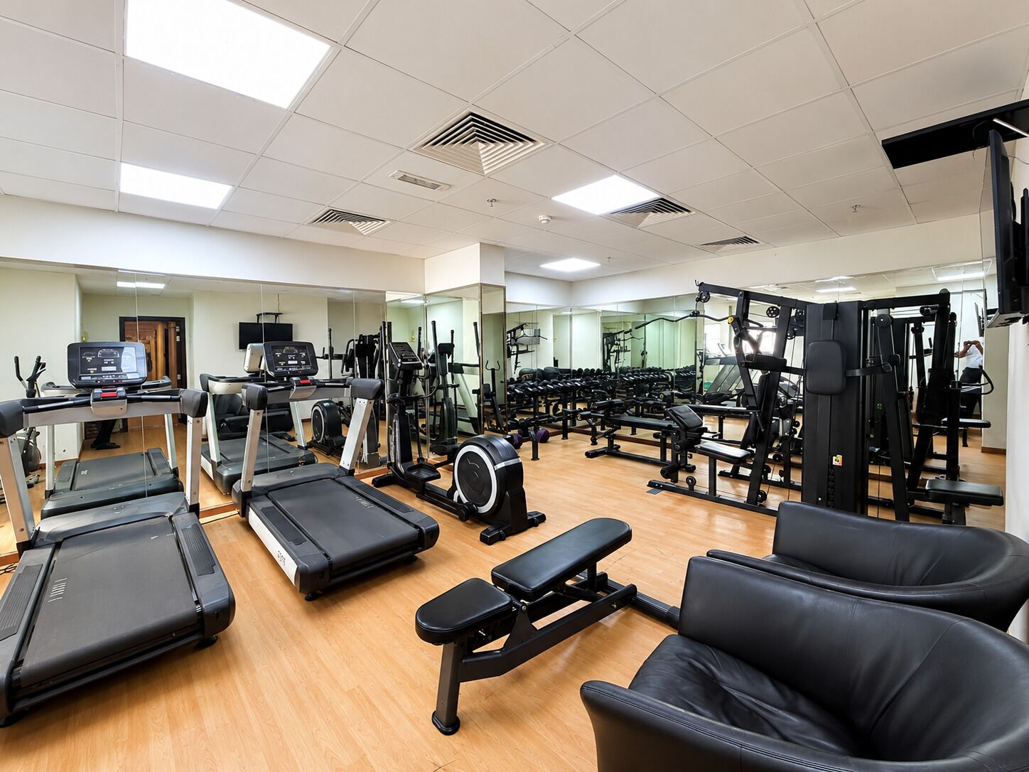 Un gimnasio con cintas de correr, elípticas y equipo de levantamiento de pesas.
