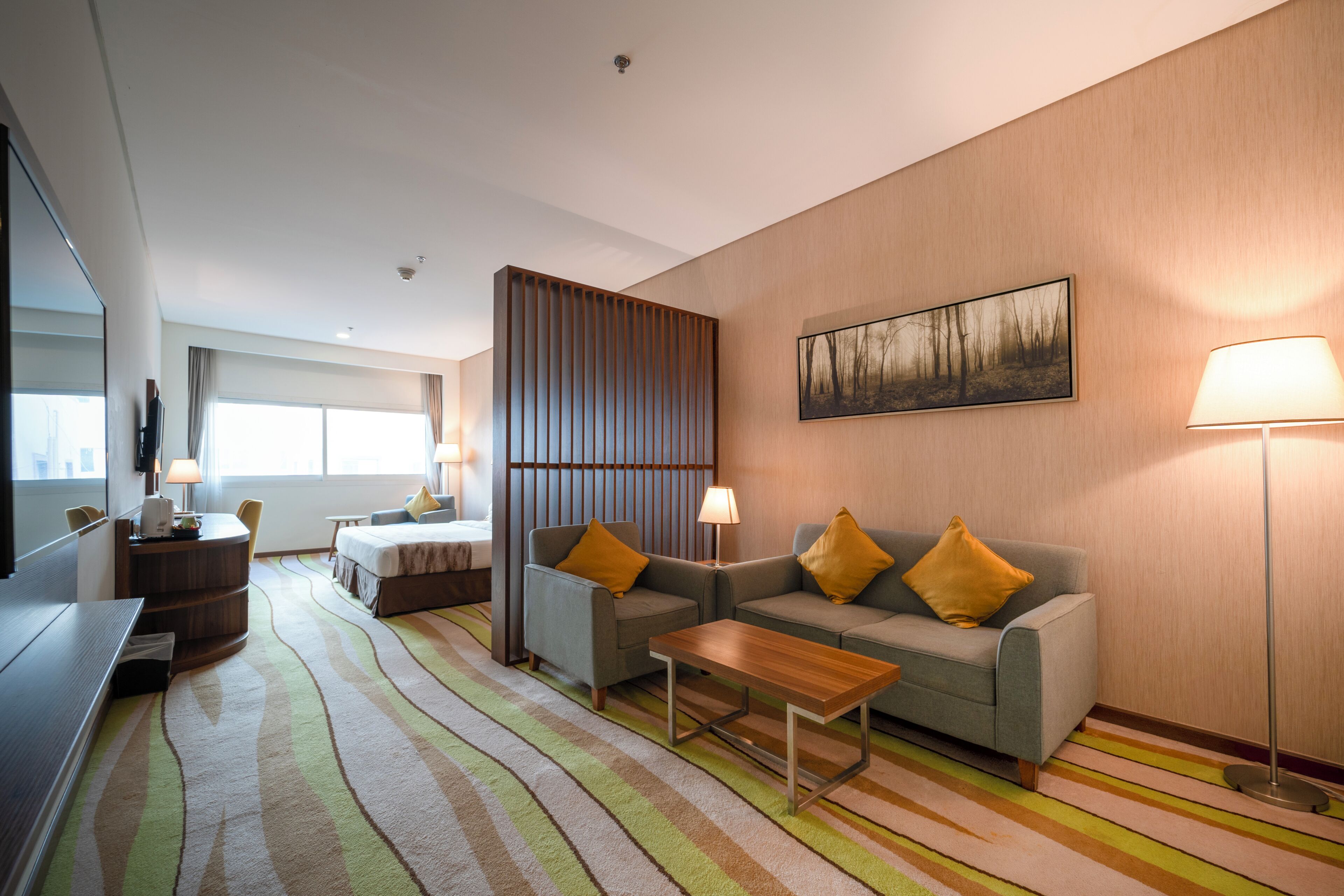 Ein modernes Hotelzimmer mit einer Couch, einem Couchtisch, einem Fernseher und einem Bett.