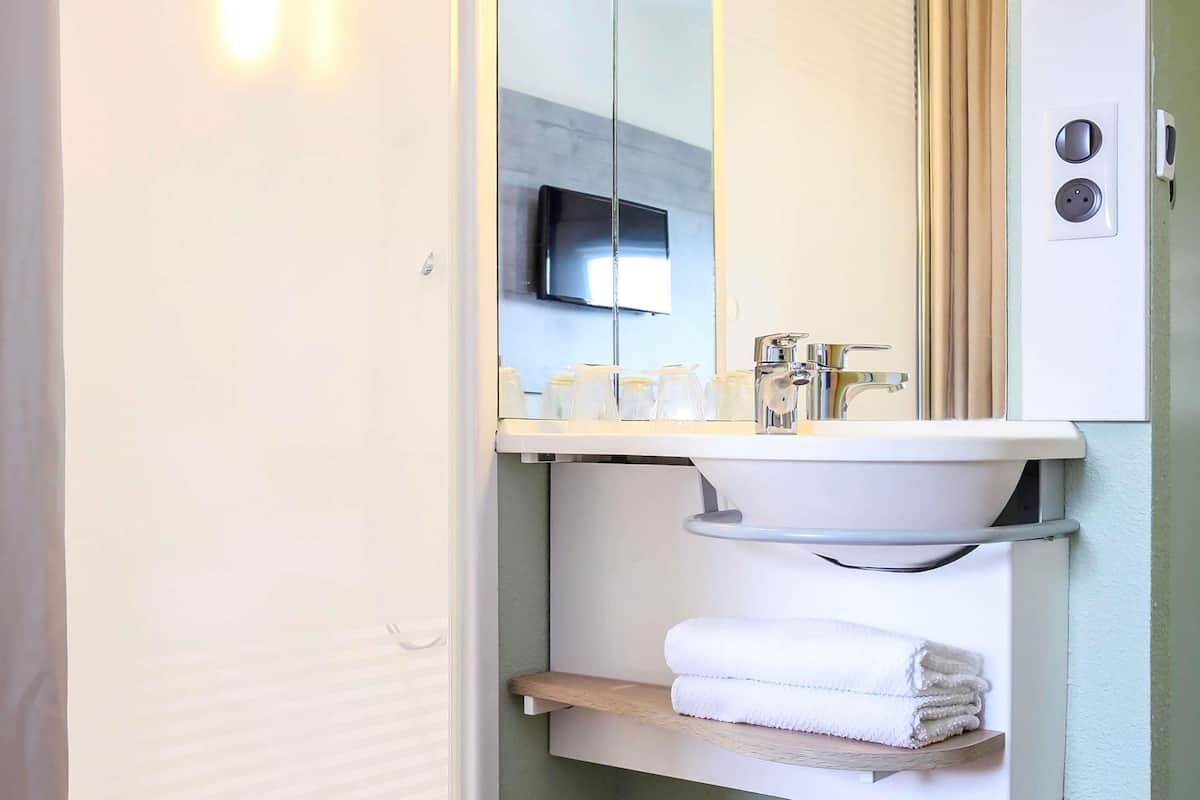 A bathroom with a white sink, mirror, and a towel rack.