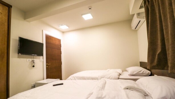 Habitación de hotel con cama, televisión montada en la pared, aire acondicionado y puerta.