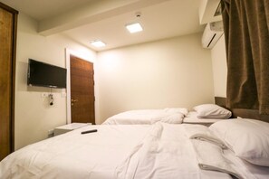 A hotel room with a bed, a TV mounted on the wall, an air conditioning unit, and a door. - Miramar Downtown hotel (Cairo)