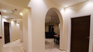 Un pasillo de hotel con piso de mármol, una puerta de madera oscura y un área de estar con sofá y mesa.