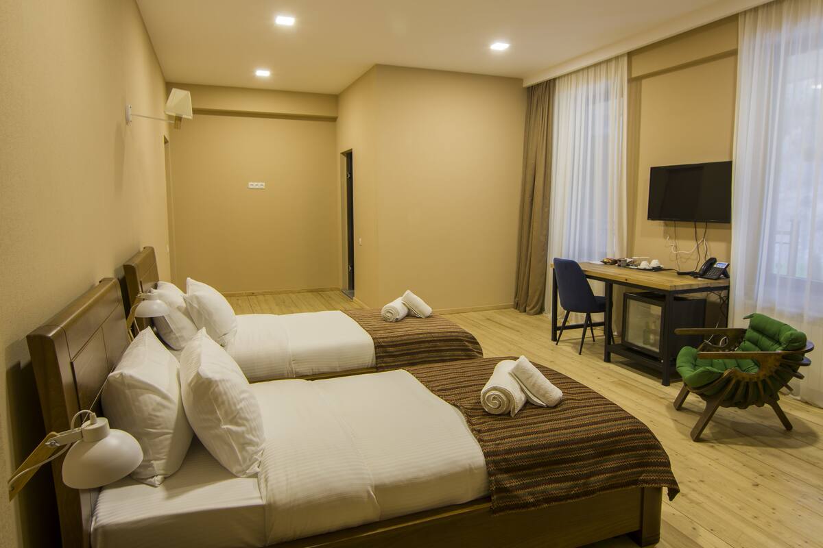 Une chambre d’hôtel avec deux lits, un bureau avec un ordinateur, une chaise et un téléviseur.