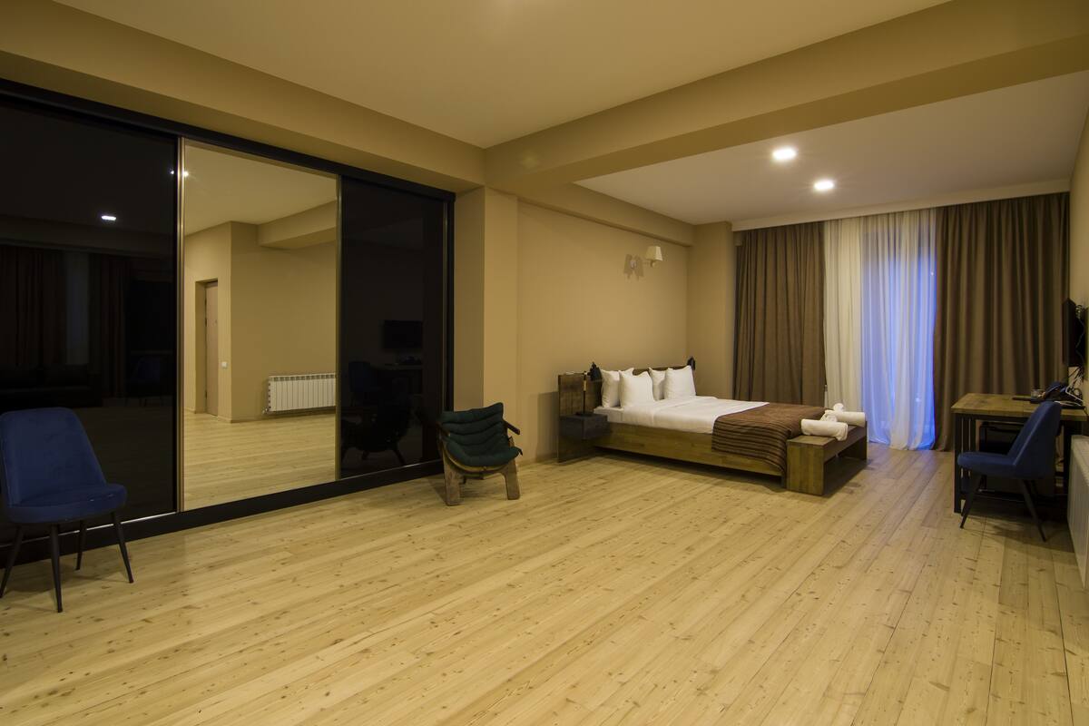 Une chambre d’hôtel avec un grand miroir, un lit, un bureau et une chaise.