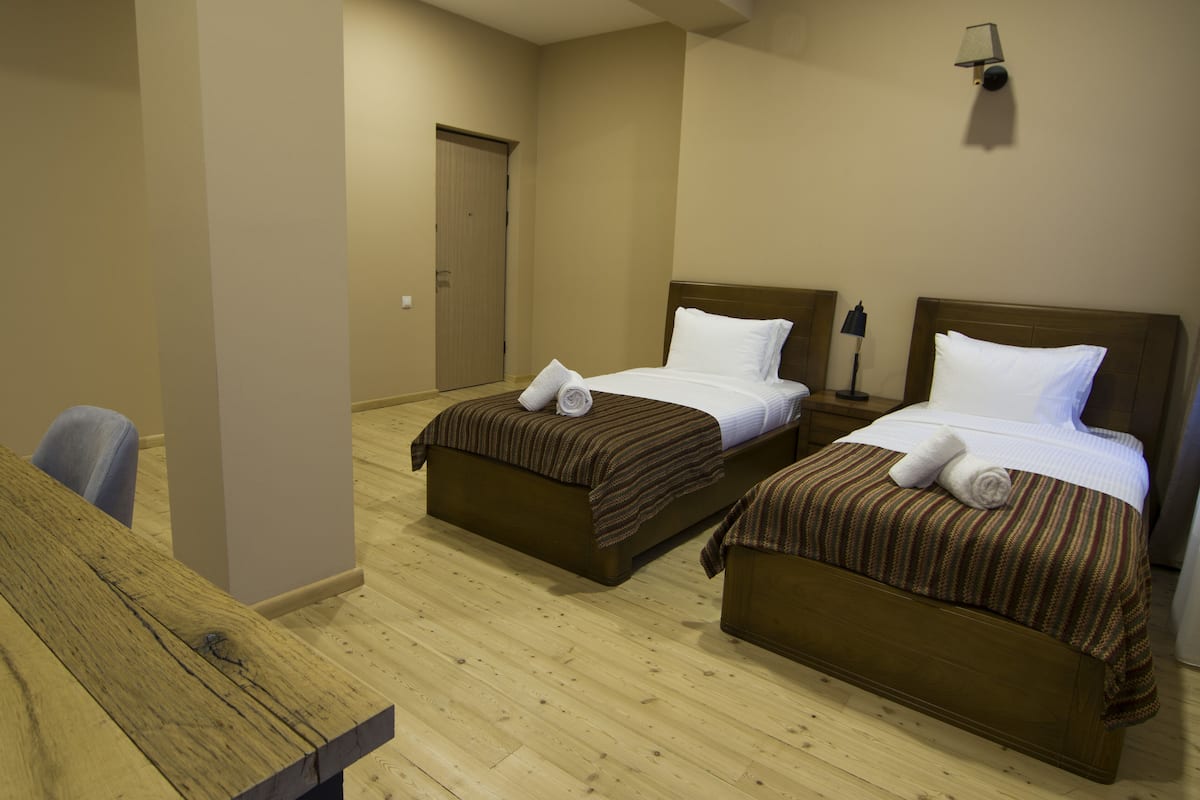 Une chambre d’hôtel avec deux lits, un bureau en bois et une porte.