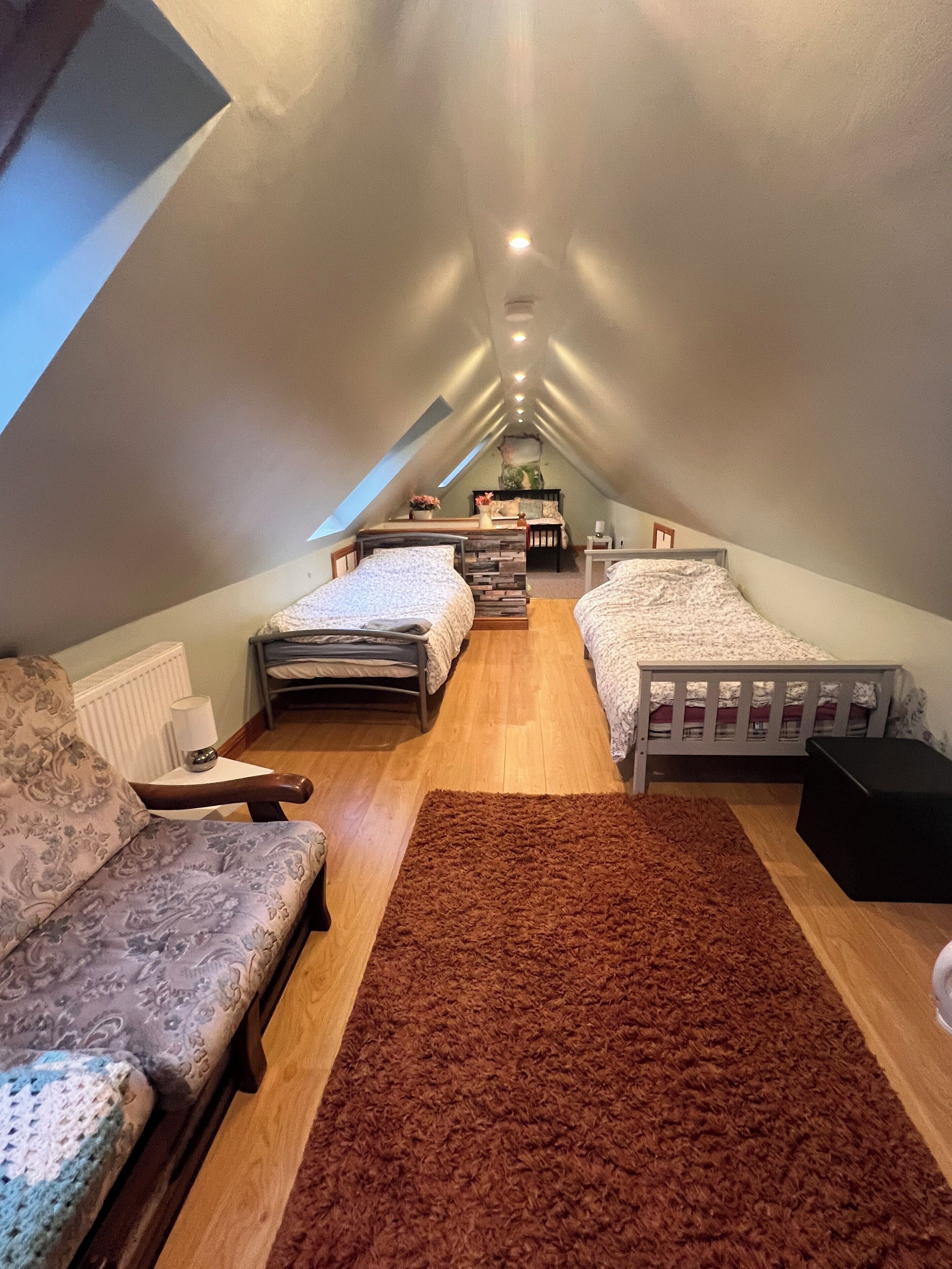 Quarto de sótão acolhedor com duas camas, uma janela grande e soalho de madeira.