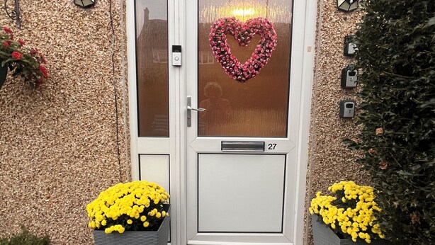 A double door with a heart-shaped decoration, numbered 27, flanked by two large flower pots. - Prelude Brigsley (Grimsby)
