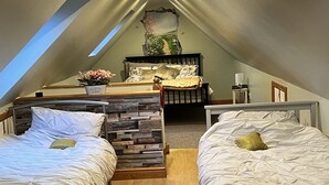 A cozy attic bedroom with two beds, a skylight, and a rustic headboard. - Prelude Brigsley (Grimsby)