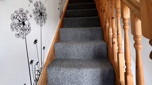 A staircase with a carpeted floor and wooden handrails, leading to a landing with a light fixture. - Prelude Brigsley (Grimsby)