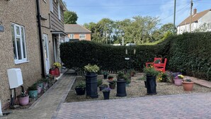 A residential area with a paved walkway, potted plants, and a red chair. - Prelude Brigsley (Grimsby)