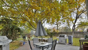 An outdoor patio with a table and chairs, a grill, and a barbecue. - Cottage by the Historic Depot (Boise)