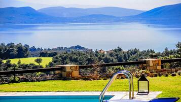 A pool with a view of a lake and mountains.