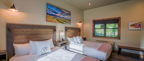 Habitación de hotel con dos camas, cabeceros de madera, un ventanal grande y un cuadro en la pared.