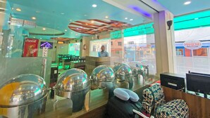 A restaurant with a counter, seating area, and a view of the street. - Hotel Readers Inn Pvt.Ltd (Kathmandu)