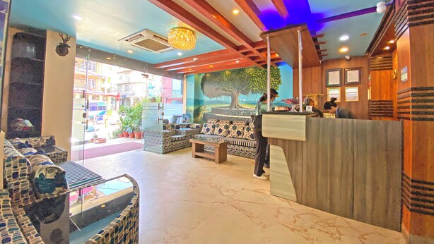 A hotel lobby with a reception desk, seating area, and a large window overlooking the street. - Hotel Readers Inn Pvt.Ltd (Kathmandu)