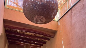 A corridor with arches, a hanging light fixture, and a bed with pillows. - Dar Boumida (Lalla Takarkoust)