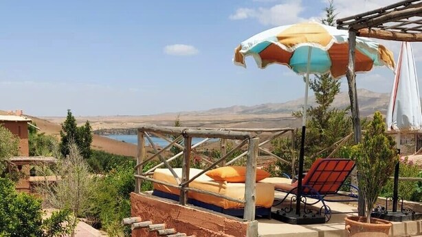 A swimming pool with a wooden deck, lounge chairs, and a view of the landscape. - Dar Boumida (Lalla Takarkoust)