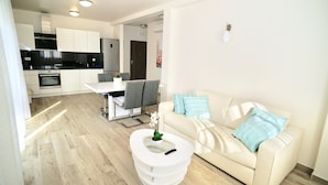 A modern living room with a white sofa, a coffee table, and a dining area with a table and chairs. - Villa Aquamarie (Trogir)