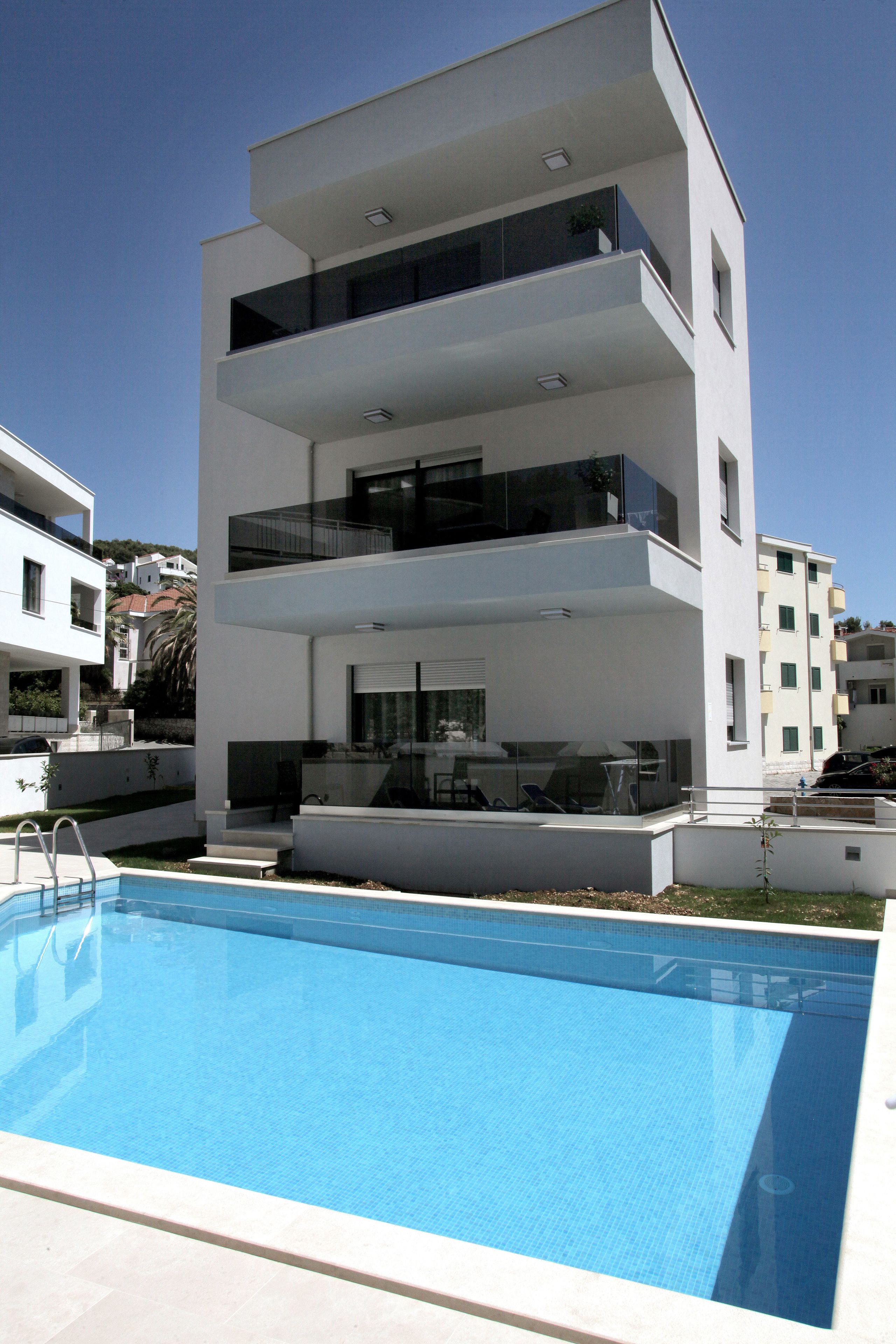 Un immeuble moderne à plusieurs étages, avec une piscine située devant.