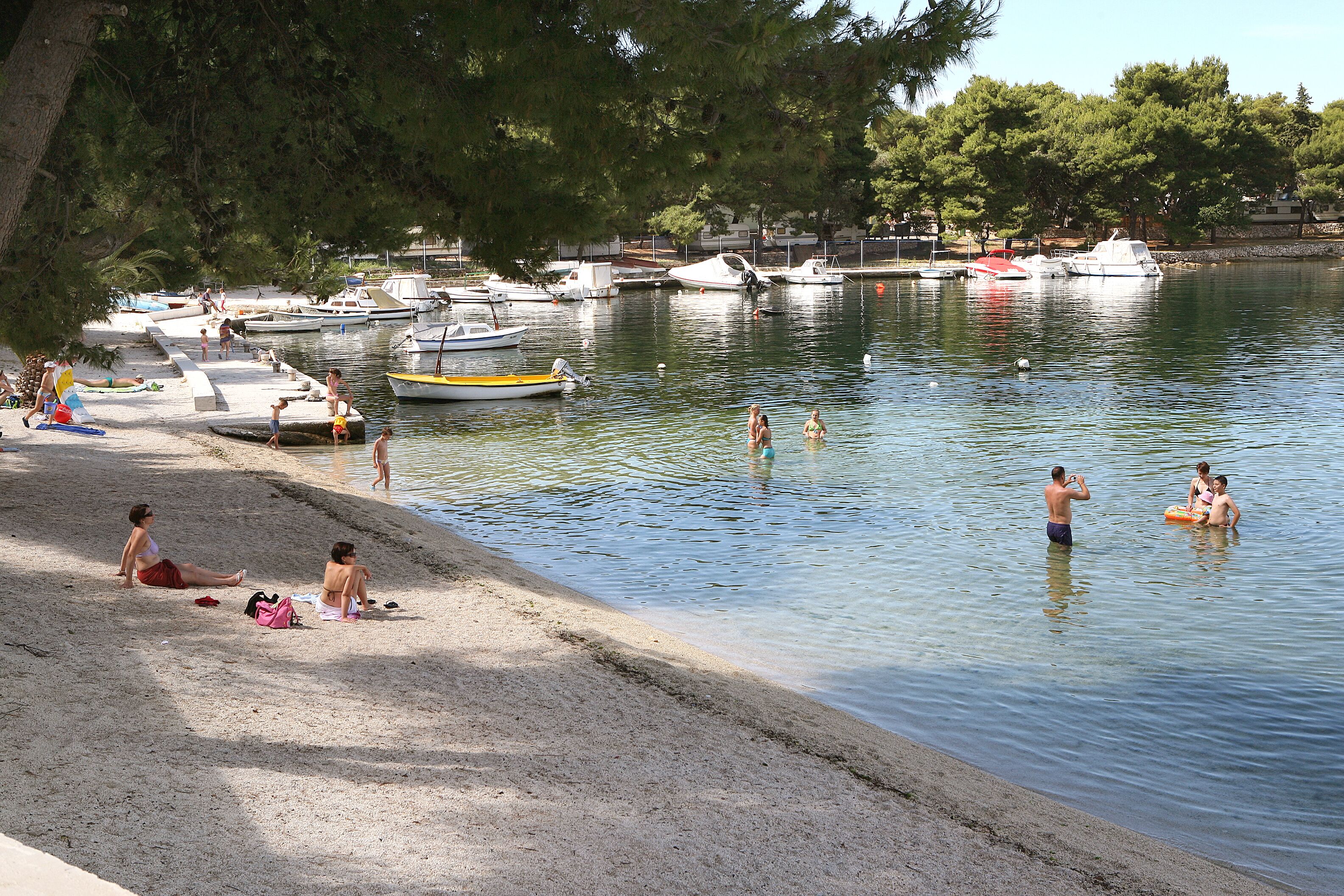 Ein Strand mit Booten, Menschen und Bäumen.