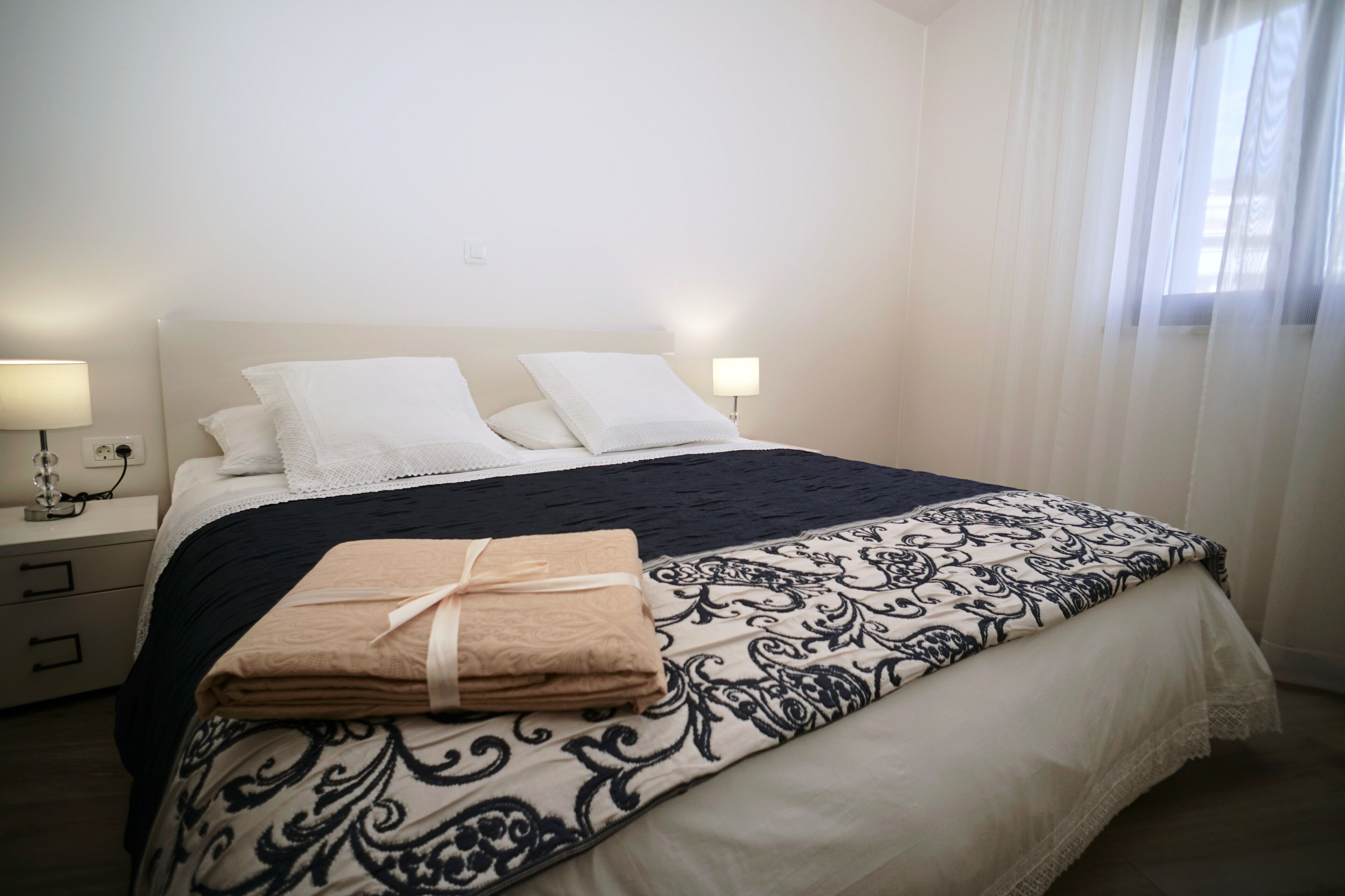 A neatly made bed with a patterned bedspread, two white pillows, and a folded beige towel on the side.