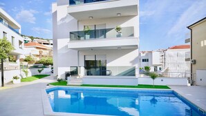 A modern two-story building with a swimming pool, balconies, and a small garden area. - Villa Aquamarie (Trogir)