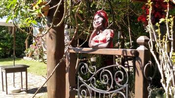 Um jardim com portão de metal, uma estátua e um caminho de tijolos.