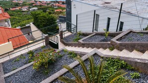 A rooftop terrace with a view of the sea, surrounded by residential buildings. - Sea View Apartment Single Beds with Swimming Pool (Arco da Calheta)