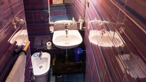 A narrow, compact bathroom with a small sink, a toilet, and a shower area. - V & V (apartment Valentina and Viviana) (Napoli)