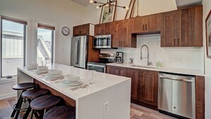 Une cuisine moderne avec des meubles en bois, des appareils en acier inoxydable et un îlot central doté de tabourets.