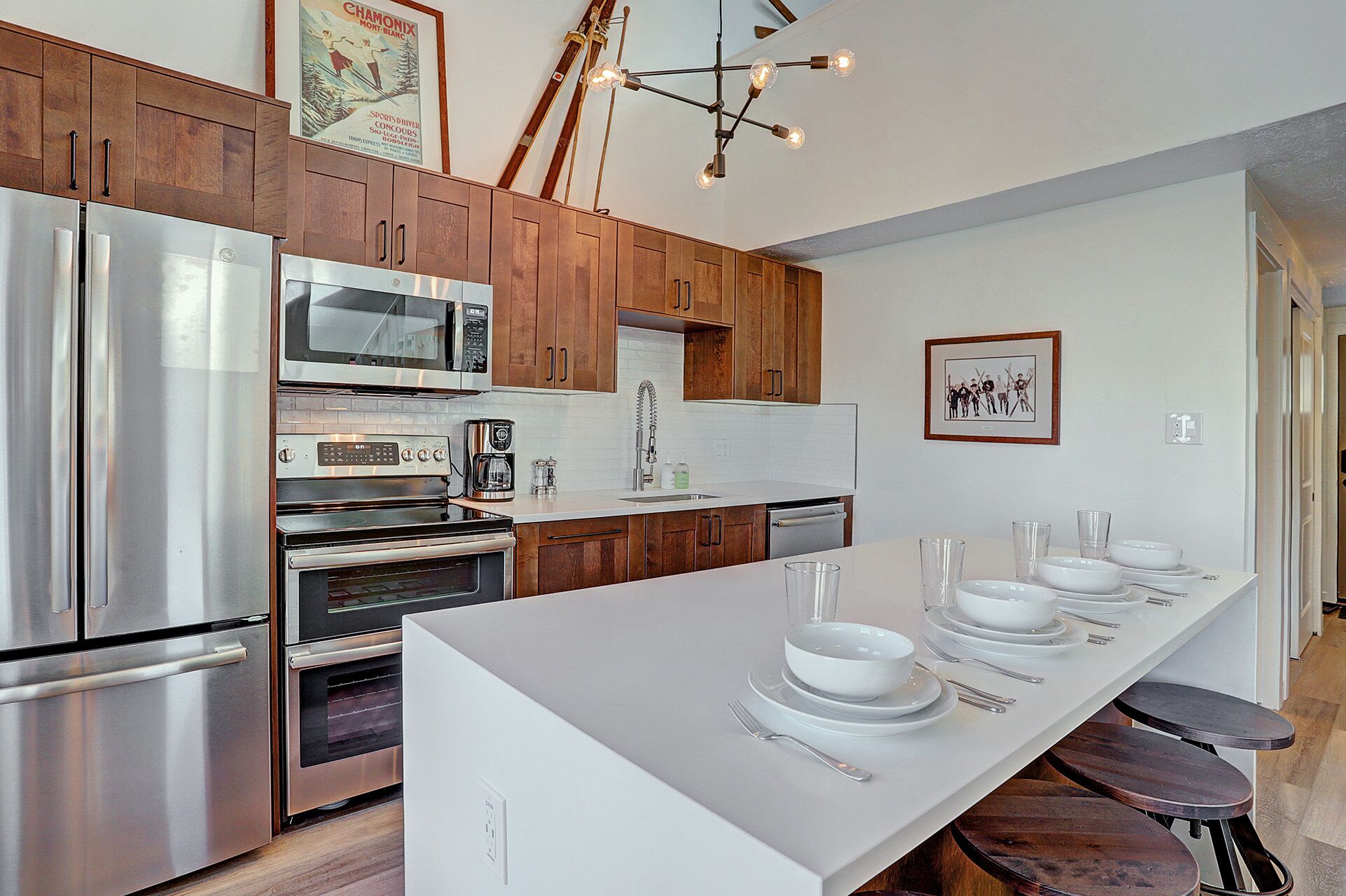 Una cocina moderna con electrodomésticos de acero inoxidable, armarios de madera y una isla central con vajilla.