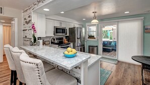 A modern kitchen with white cabinets, stainless steel appliances, and a marble countertop. - Waterfront -Canal, Heated Pool, Tiki Bar, Free 6P Golf Cart Promo Ends 8/31! (Anna Maria)