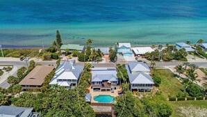 A coastal residential area with houses, a swimming pool, and a view of the ocean. - Waterfront -Canal, Heated Pool, Tiki Bar, Free 6P Golf Cart Promo Ends 8/31! (Anna Maria)
