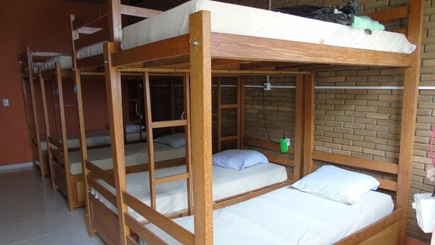 A dormitory room with bunk beds, a brick wall, and a tiled floor. - Amazon Eco Hostel (Iranduba)