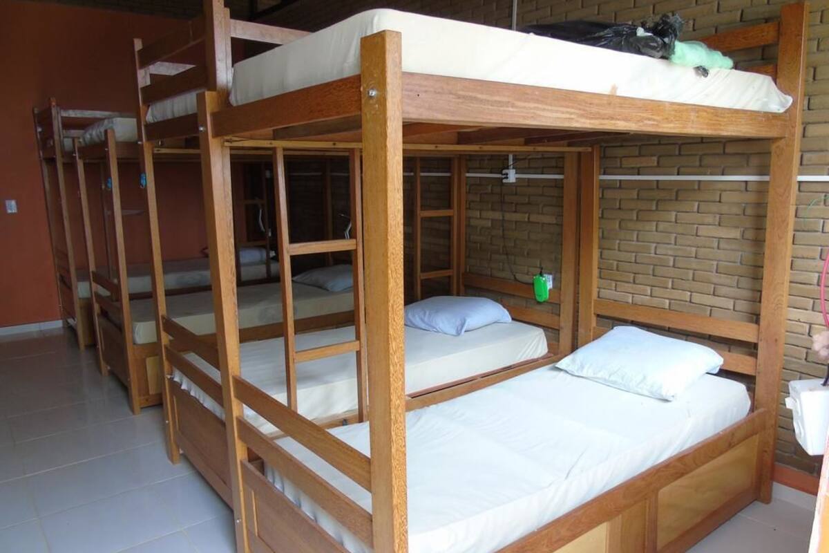 Un dormitorio con literas, una pared de ladrillo y suelo de baldosas.