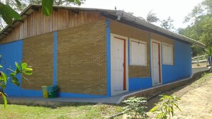A single-story building with a brick exterior and blue trim. It features a front door and two windows. - Amazon Eco Hostel (Iranduba)