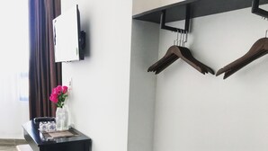 Un couloir avec un comptoir noir, un miroir, un téléviseur fixé au mur, un porte-chaussures et un banc.