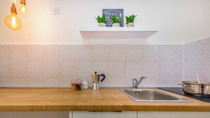 A kitchen with a wooden countertop, a stainless steel sink, and a white tiled backsplash. - Rijeka Apartments Terra City Center (Rijeka)