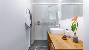 A modern bathroom with a glass shower enclosure, a wooden vanity with a sink, and a mirror. - Rijeka Apartments Terra City Center (Rijeka)
