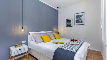 Un dormitorio moderno con cama, mesita de noche e iluminación en la pared.