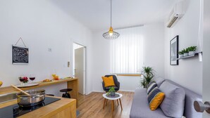 A modern kitchen with a stove, a dining table, and a sofa in the living area. - Rijeka Apartments Terra City Center (Rijeka)